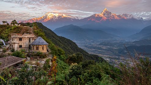 Blick auf die im Tal liegende Stadt Pokhara und das dahinter liegende Himalaya-Gebirge