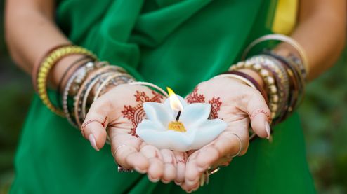 Woman in green dress holding lotus flower shaped candle